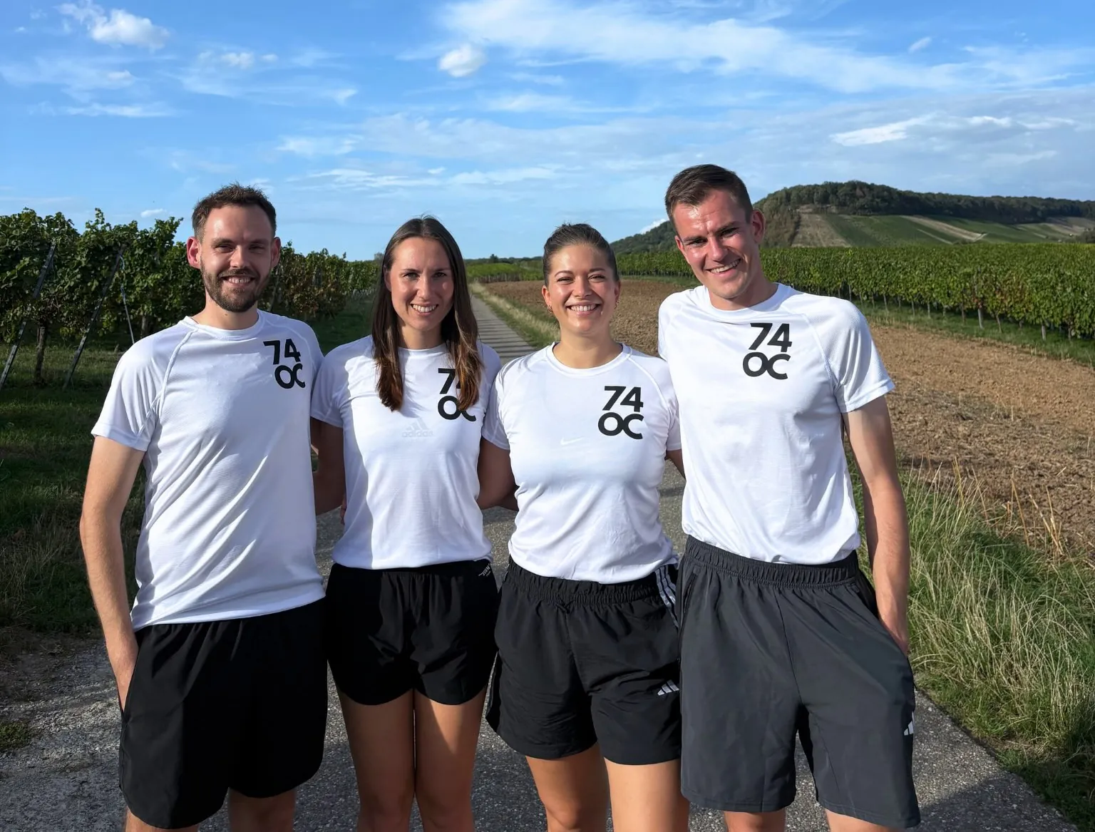 Simon, Lisa, Jenny und Mari Arm in Arm auf einem Feldweg zwischen Weinbergen