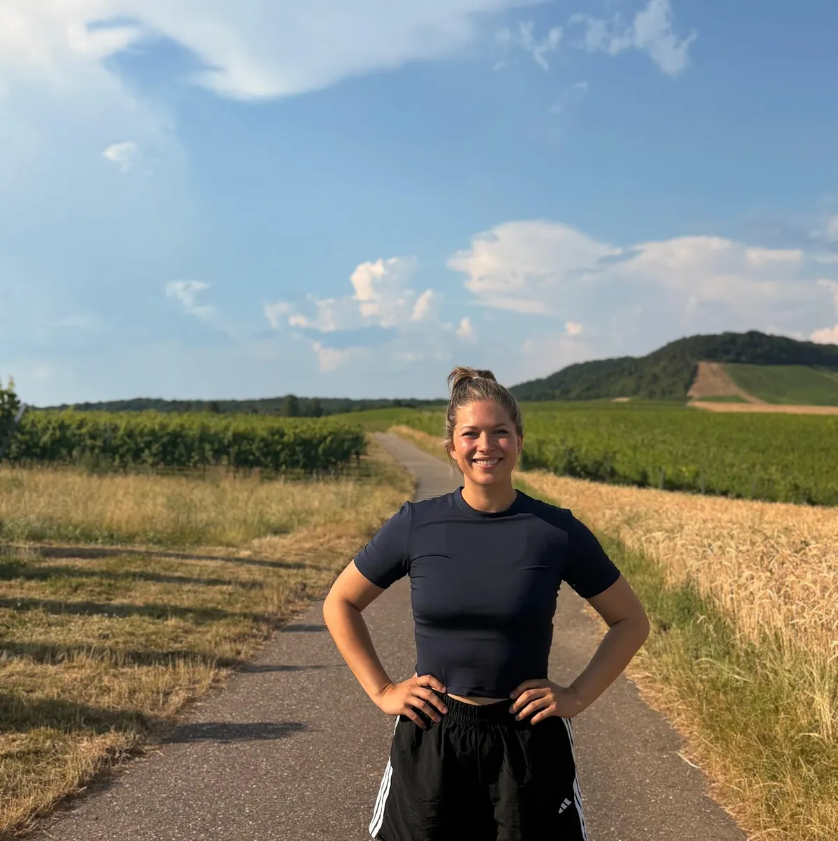 Jenny auf einem Feldweg zwischen Weinbergen und Kornfeld